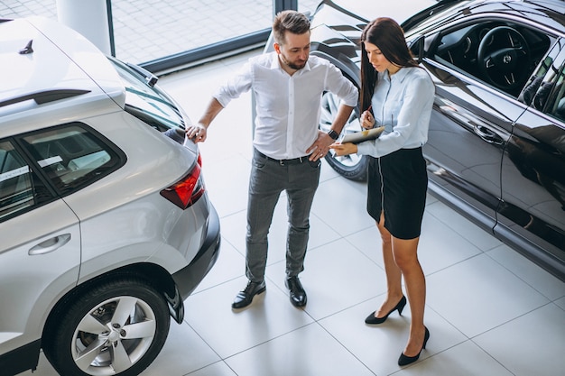 Salesman and woman looking for a car in a car showroom