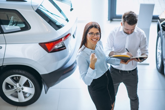 Salesman and woman looking for a car in a car showroom