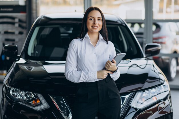 Saleswoman in car showroom selling cars