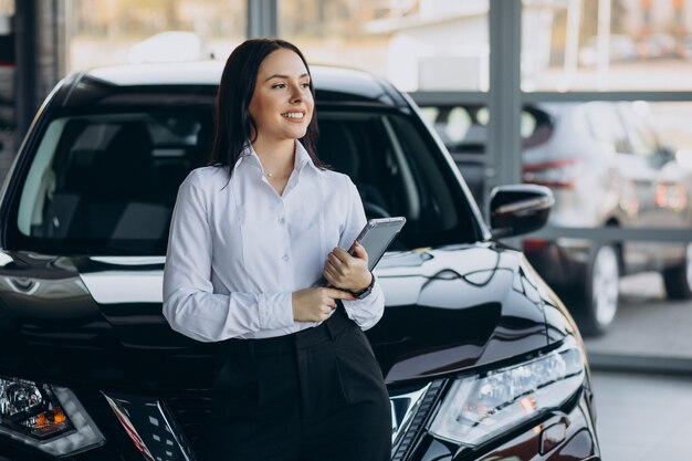 Saleswoman in car showroom selling cars