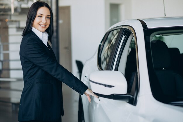 Saleswoman in car showroom selling cars