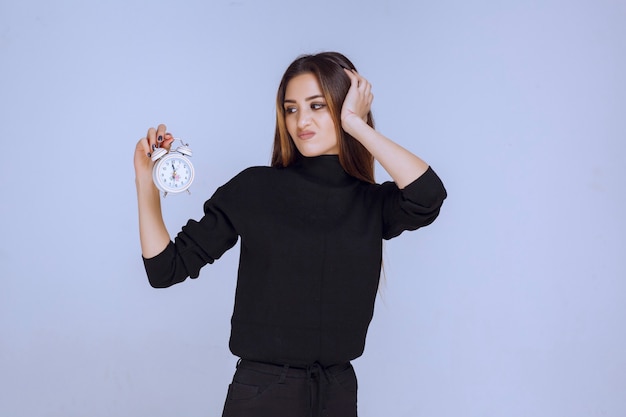 Free photo a saleswoman holding an alarm clock and promoting it.