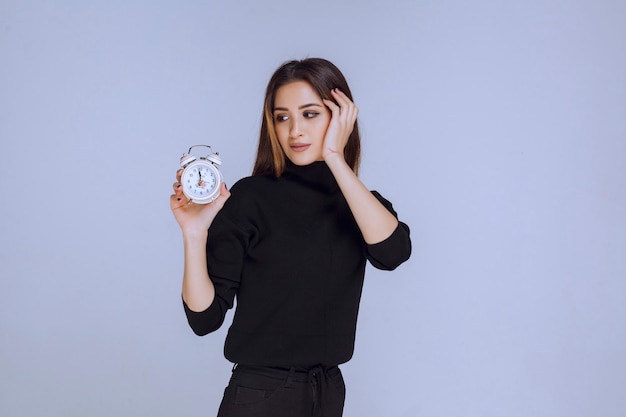 A saleswoman holding an alarm clock and promoting it. 