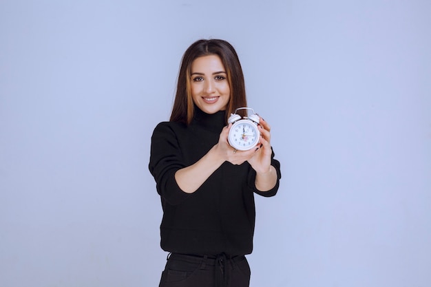 A saleswoman holding an alarm clock and promoting it. 