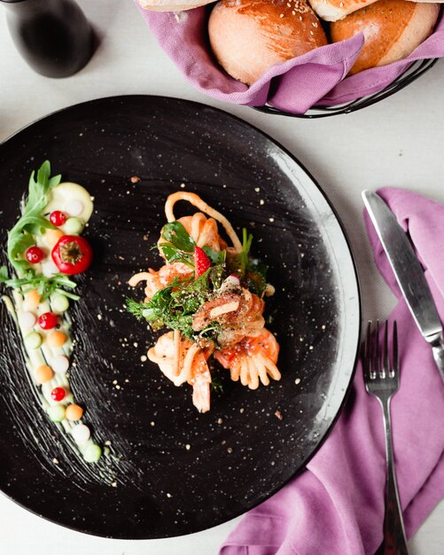 Salmon fillet salad with white cream sauce inside black plate.