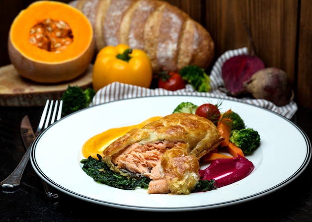 Salmon pie served with roasted herbs, vegetables and sour sauce