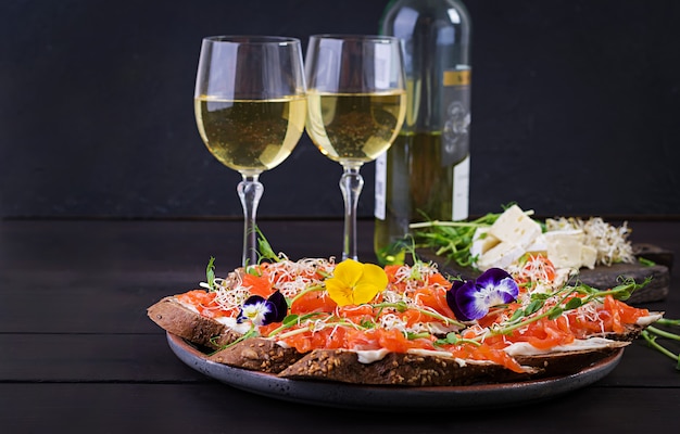 Salmon sandwiches with cream cheese and microgreen on wooden table.