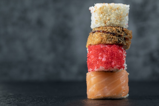 Salmon sushi rolls isolated on black table.