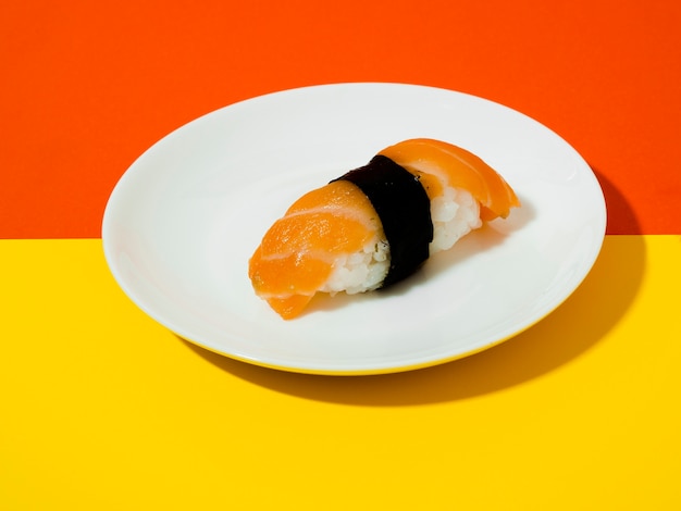 黄色とオレンジ色の背景に白い皿にサーモン寿司