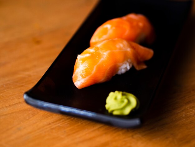 Salmon sushi with wasabi on a black plate