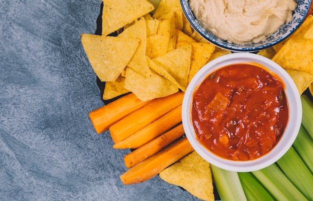 Salsa sauce in bowl over carrot; celery stem and tortilla chips in plate