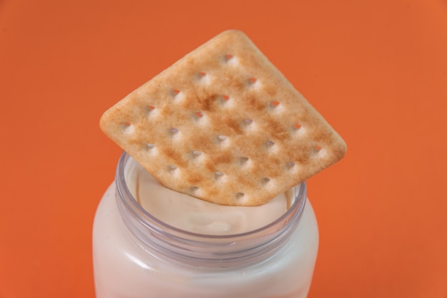 Salt cracker with mayonnaise on the orange table