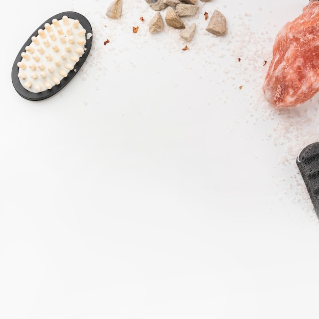 Salt; massage brush; pumice stone and himalayan pink rock salt isolated on white backdrop