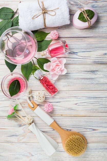 Salt; oil; towel; soap; leaves; flowers and brush on wooden plank