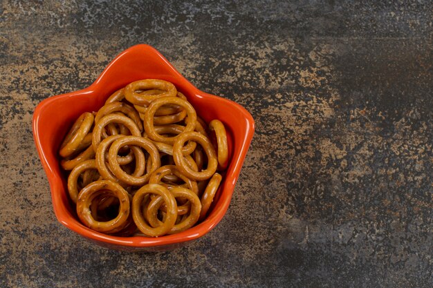 Salted circle pretzels in orange bowl.