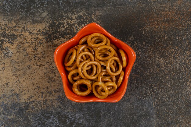 Salted circle pretzels in orange bowl.