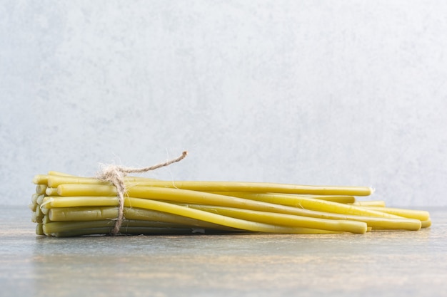 Salty delicious vegetable in rope on white background