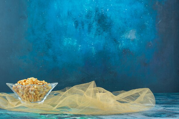 Salty fish crackers in glass bowl on tulle, on the marble table.