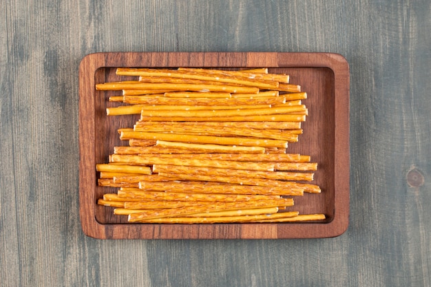 Salty pretzel sticks on wooden plate