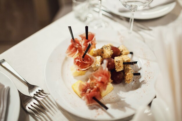 Salty snacks of meet and bread put on white plate