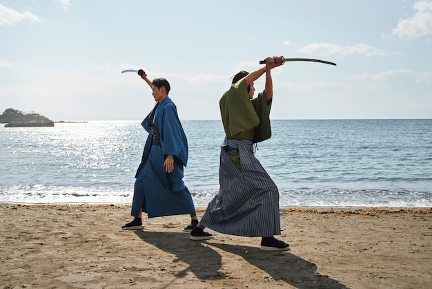 Foto gratuita samurai che combatte con le spade sulla spiaggia