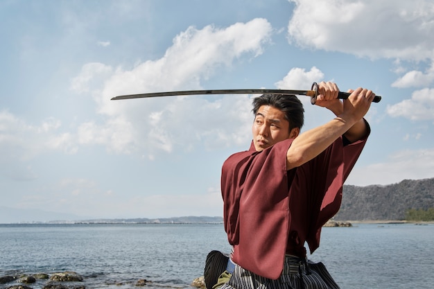 Foto gratuita samurai con la spada in spiaggia
