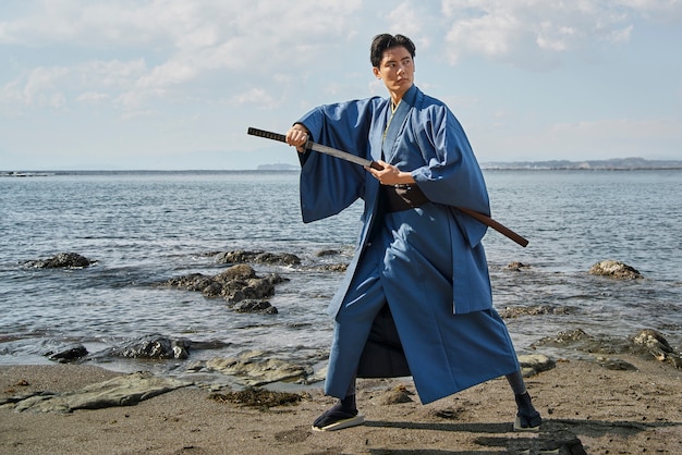 Foto gratuita samurai con la spada in spiaggia