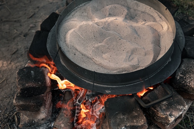 Песок нагревают на огне, чтобы приготовить кофе