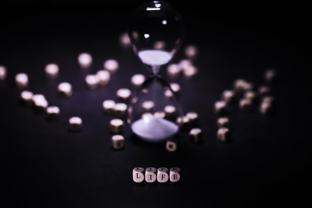 Sand running through the bulbs of an hourglass measuring the passing time in a countdown to a deadline on a dark table background with copy space