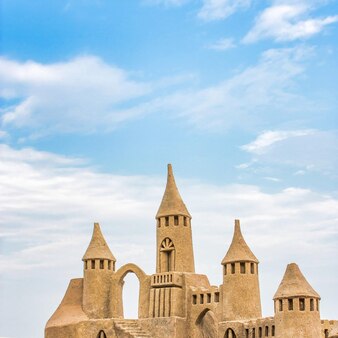 Замок из песка в солнечный день на фоне голубого неба. концепция лета, отдыха, отдыха и развлечений.