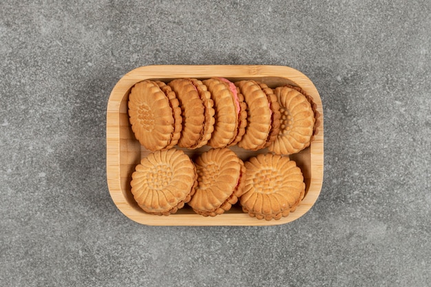 Sandwich cookies filled with cream on wooden plate