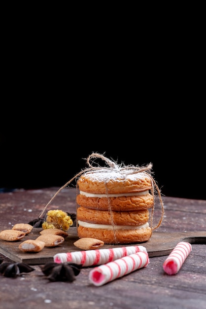 sandwich cookies with cream along with stick candies on brown desk