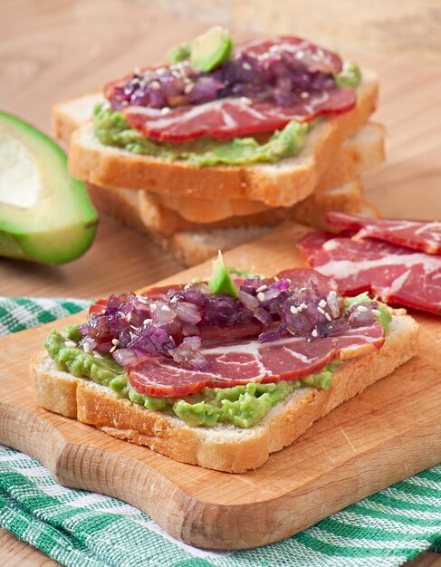 Sandwich with ham, avocado sauce and caramelized onions