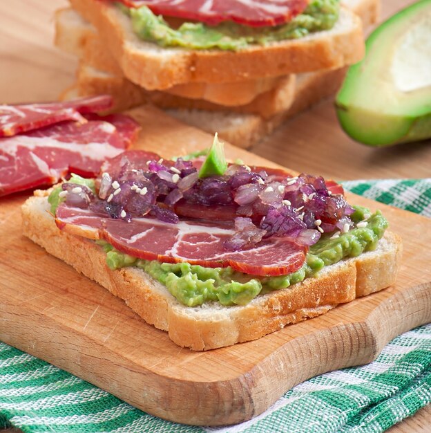 Sandwich with ham, avocado sauce and caramelized onions