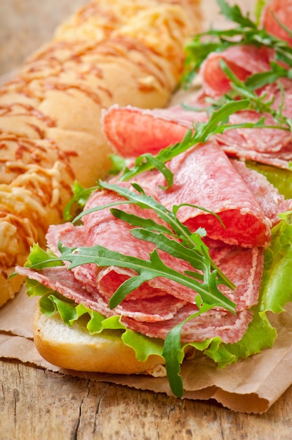 Foto gratuita panino con salame, lattuga, pomodoro e rucola