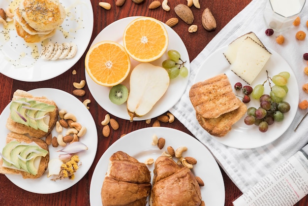 Sandwiches; fruits; dry fruits on plate over wooden table