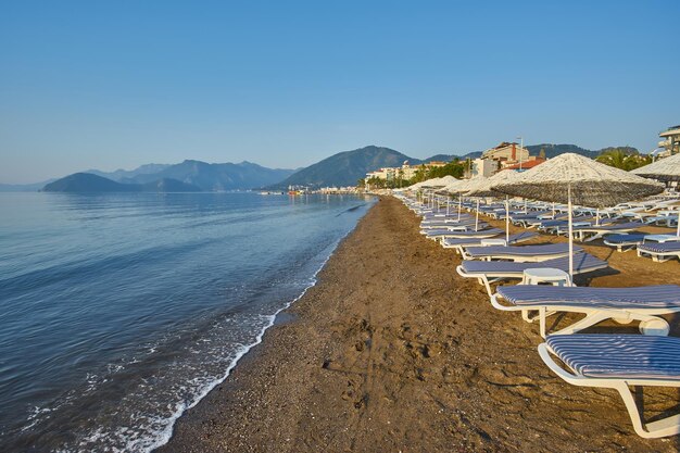Sandy beach without people and with sun loungers umbrellas palm trees Marmaris