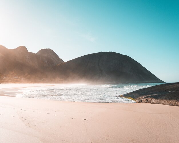 Песчаный берег красивого моря с ясным голубым небом и солнечным светом