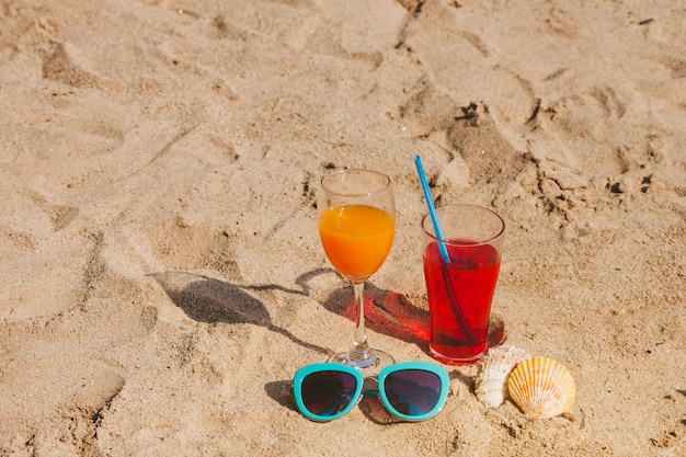 음료와 선글라스가 달린 모래 표면