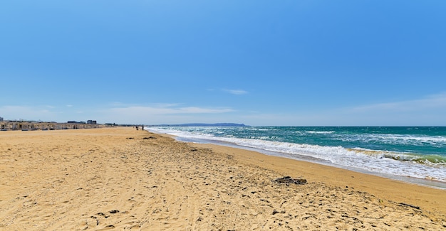 砂浜の野生のビーチ、雲と青い空の青い海がぼやけ、海岸に焦点を当てています。美しい青い海の屋外の自然の風景、