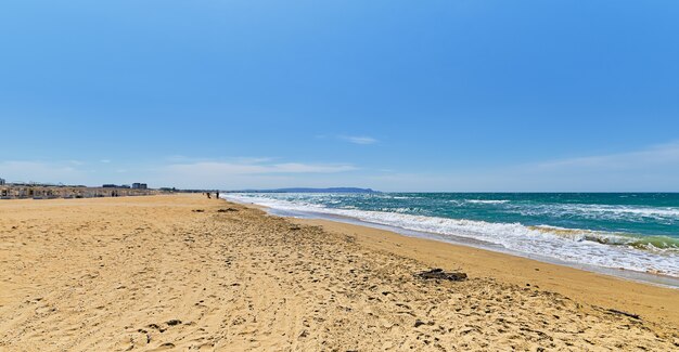 砂浜の野生のビーチ、雲と青い空の青い海がぼやけ、海岸に焦点を当てています。美しい青い海の屋外の自然の風景、