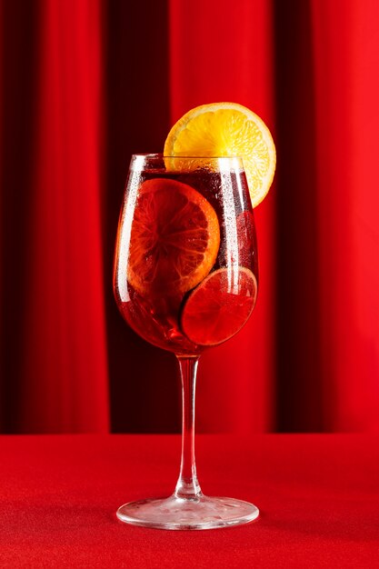 Sangria drink with lemon slice on red background