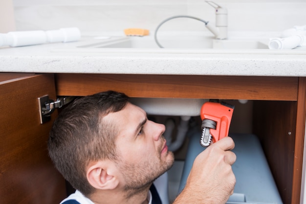 Foto gratuita tecnico sanitario che lavora con la chiave sulla cucina