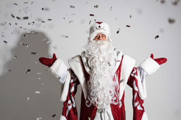 Santa claus under festive xmas confetti showing welcome gesture