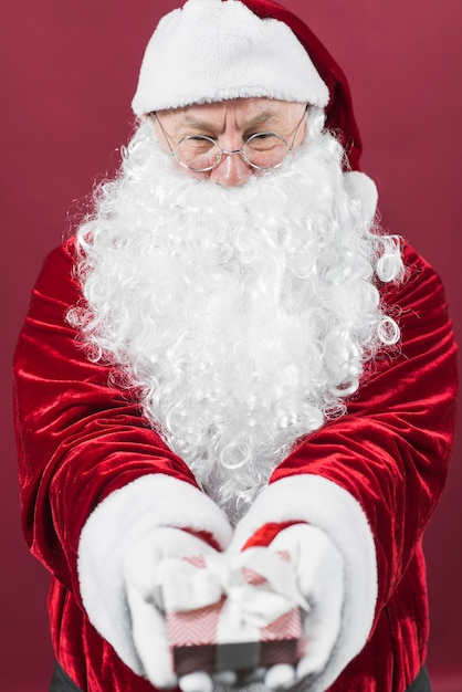 Santa Claus in glasses holding small gift box