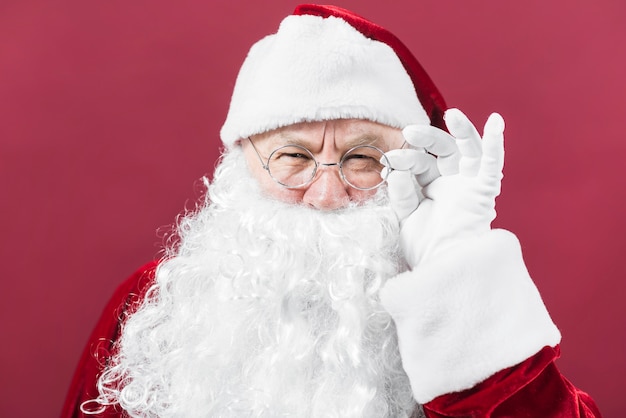 Santa claus in glasses peeping on red background