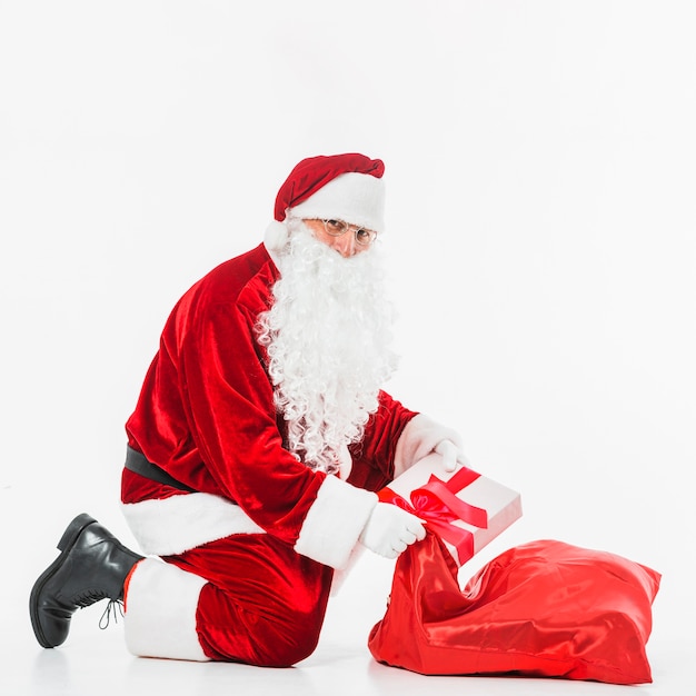 Santa Claus in glasses putting gift box in sack