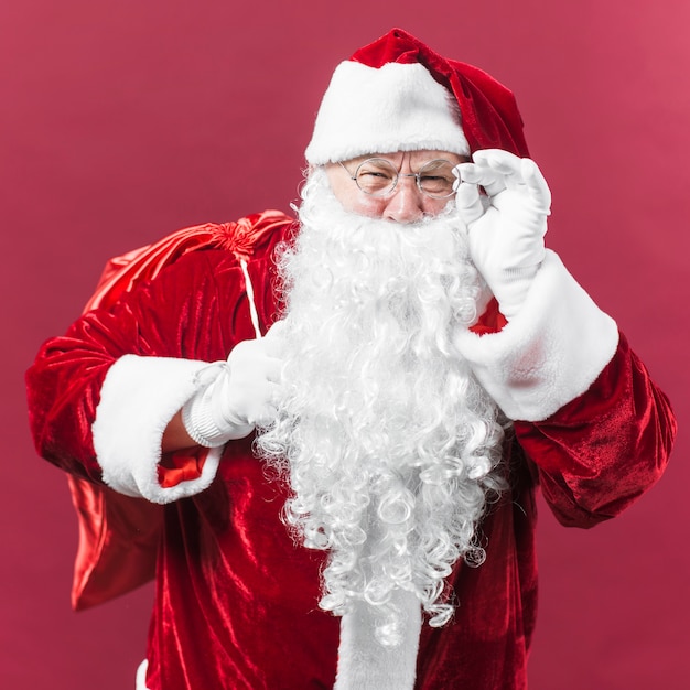Santa Claus in glasses with sack behind back 