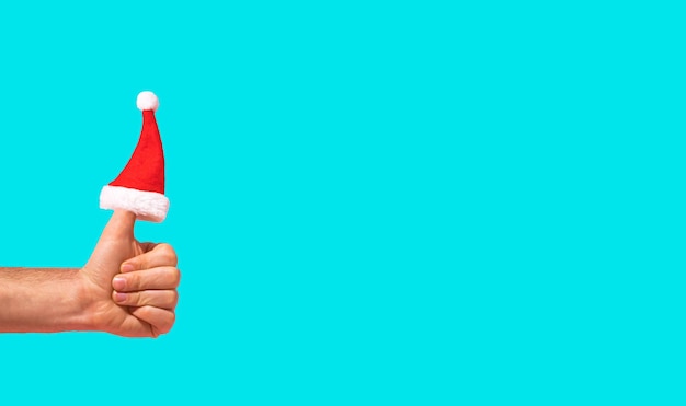 Santa claus hat is put on the finger hand is holding thumbs up  new year idea copy space