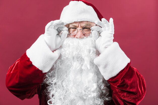 Santa Claus in hat peeping on red background